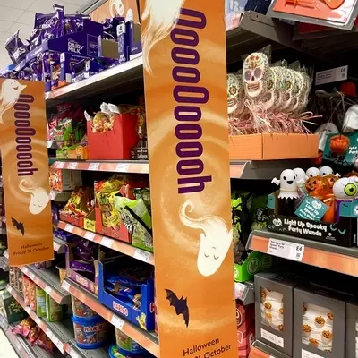 signage for Waitrose with hand illustrated ghosts and bats on an illustrated orange background 